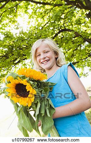 Smiling girl carrying sunflowers View Large Photo Image Stock Photo - Smiling girl carrying sunflowers. Fotosearch