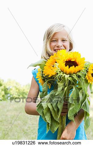 Stock Photograph - Smiling girl carrying sunflowers. Fotosearch