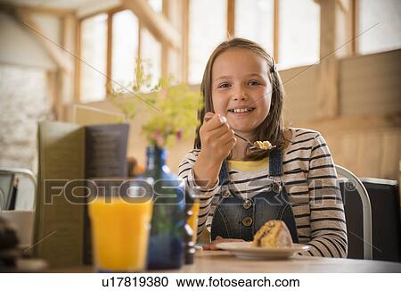 Smiling girl eating breakfast at table View Large Photo Image Stock Image - Smiling girl eating breakfast at table. Fotosearch