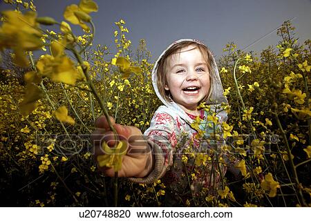 Stock Image - Smiling girl playing in field of flowers. Fotosearch