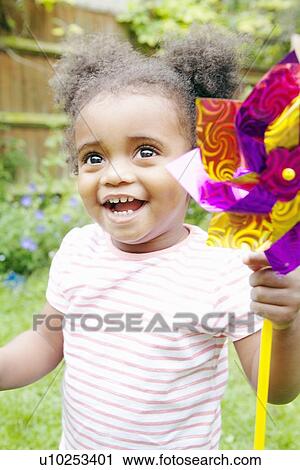 Stock Image - Smiling girl playing with pinwheel. Fotosearch