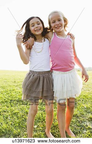 Stock Image - Smiling girls hugging outdoors. Fotosearch