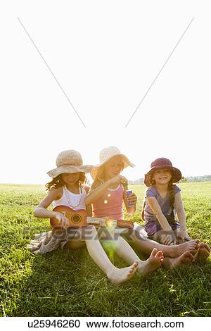 Smiling girls relaxing in grass View Large Photo Image Stock Image - Smiling girls relaxing in grass. Fotosearch