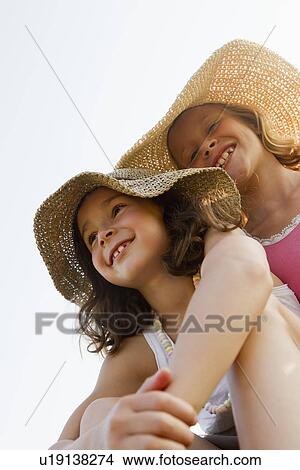 Picture - Smiling girls wearing sunhats outdoors. Fotosearch