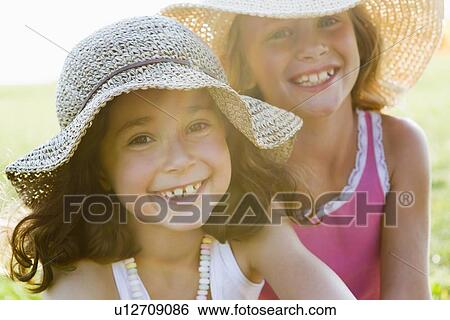 Stock Photograph - Smiling girls wearing sunhats outdoors. Fotosearch