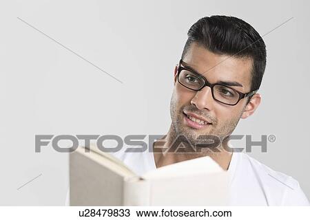 Stock Image - Smiling man reading book. Fotosearch