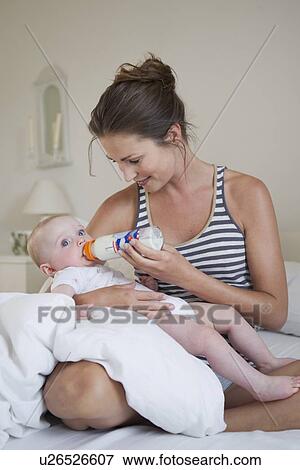 Smiling mother bottle feeding baby View Large Photo Image Stock Photo - Smiling mother bottle feeding baby. Fotosearch