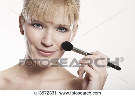 Stock Image - Smiling woman applying makeup. Fotosearch