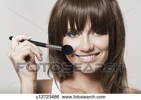 Smiling woman applying makeup View Large Photo Image Stock Photograph - Smiling woman applying makeup. Fotosearch
