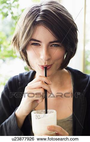 Stock Photograph - Smiling woman drinking through straw. Fotosearch