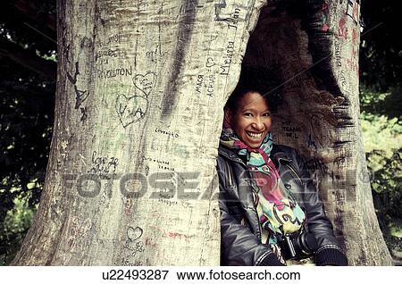 Smiling woman hiding in carved tree View Large Photo Image Stock Photo - Smiling woman hiding in carved tree. Fotosearch