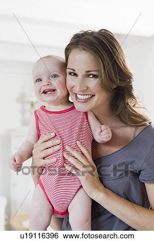 Stock Photograph - Smiling woman holding baby. Fotosearch