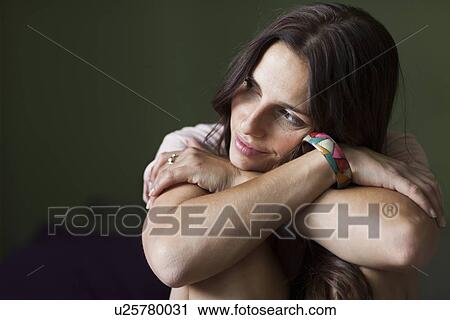 Stock Image - Smiling woman hugging her knees. Fotosearch