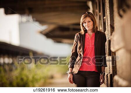 Smiling woman leaning against wall View Large Photo Image Stock Photograph - Smiling woman leaning against wall. Fotosearch