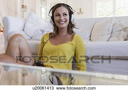 Stock Image - Smiling woman listening to headphones. Fotosearch