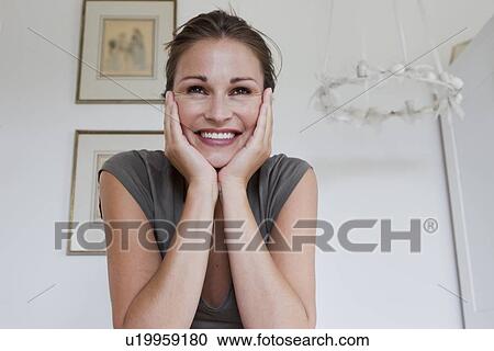 Stock Image - Smiling woman resting chin in hands. Fotosearch