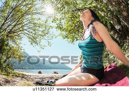 Smiling woman sitting by rural lake View Large Photo Image Stock Photo - Smiling woman sitting by rural lake. Fotosearch