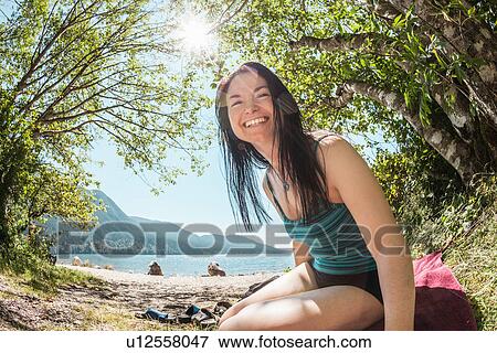 Smiling woman sitting by rural lake View Large Photo Image Stock Photo - Smiling woman sitting by rural lake. Fotosearch