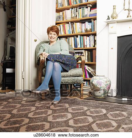 Stock Photo - Smiling woman sitting in armchair. Fotosearch