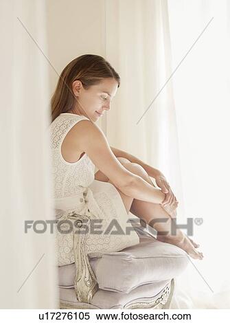 Stock Photography - Smiling woman sitting in armchair. Fotosearch