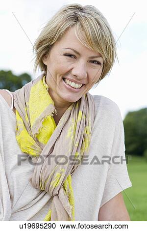 Stock Image - Smiling woman sitting in park. Fotosearch