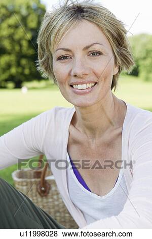 Smiling woman sitting in park View Large Photo Image Stock Photo - Smiling woman sitting in park. Fotosearch
