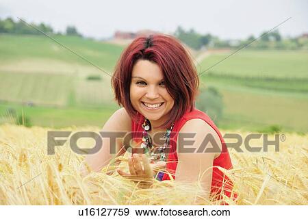 Smiling woman sitting in tall grass View Large Photo Image Stock Photo - Smiling woman sitting in tall grass. Fotosearch