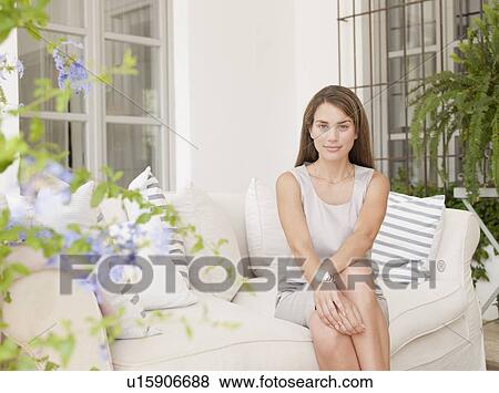 Stock Photo - Smiling woman sitting on sofa. Fotosearch