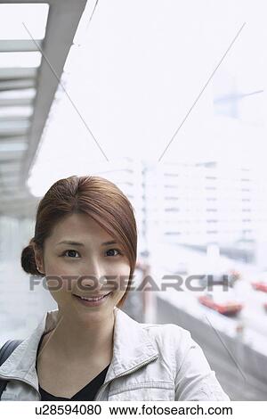 Stock Image - Smiling woman standing on city street. Fotosearch