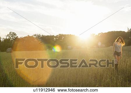 Stock Photograph - Smiling woman walking in grassy field. Fotosearch