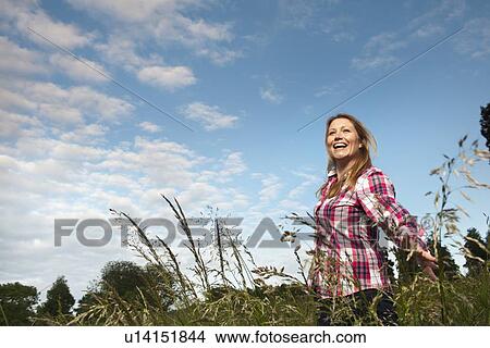 Smiling woman walking in tall grass View Large Photo Image Picture - Smiling woman walking in tall grass. Fotosearch
