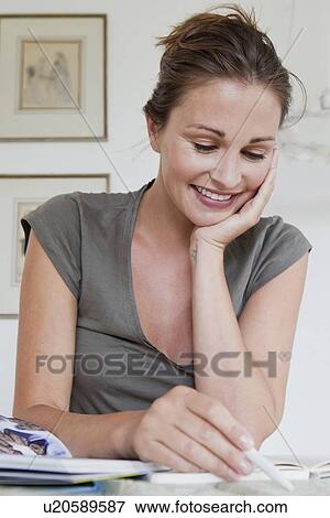 Stock Photo - Smiling woman writing at desk. Fotosearch