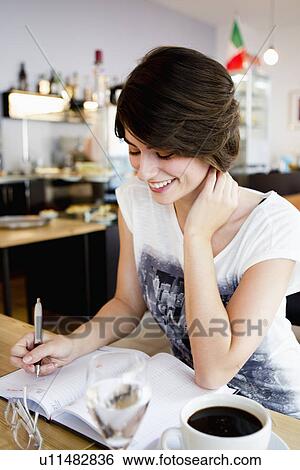 Smiling woman writing in cafe View Large Photo Image Stock Photograph - Smiling woman writing in cafe. Fotosearch