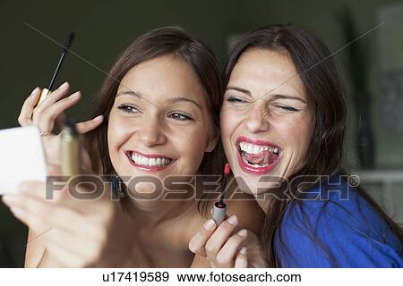 Smiling women applying makeup in mirror View Large Photo Image Stock Photo - Smiling women applying makeup in mirror. Fotosearch
