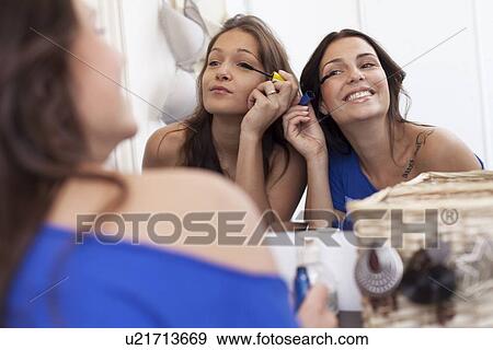 Smiling women applying makeup in mirror View Large Photo Image Stock Photo - Smiling women applying makeup in mirror. Fotosearch
