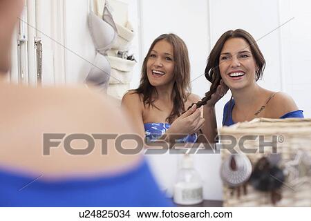 Picture - Smiling women doing hair in mirror. Fotosearch