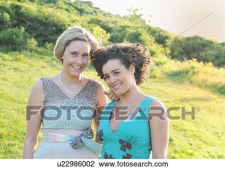Stock Image - Smiling women standing in meadow. Fotosearch