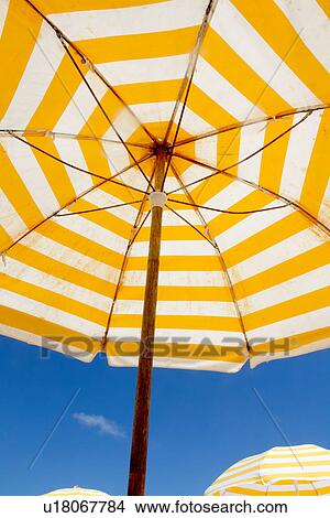 Picture - Striped umbrella under blue sky. Fotosearch