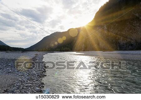 Stock Photo - Sun setting over rocky river. Fotosearch