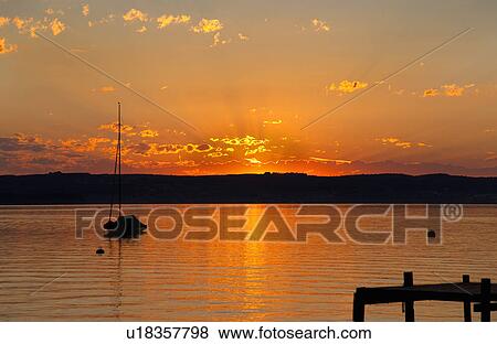 Sun setting over still rural lake View Large Photo Image Stock Photo - Sun setting over still rural lake. Fotosearch