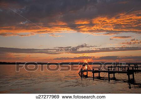 Stock Photo - Sun setting over still rural lake. Fotosearch
