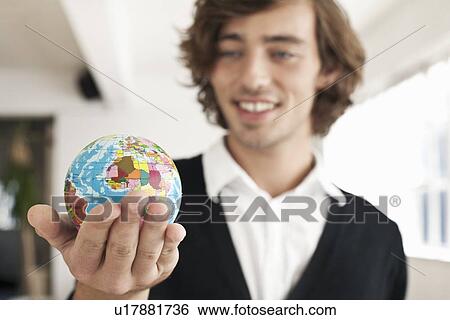 Teenage boy holding miniature globe View Large Photo Image Stock Photograph - Teenage boy holding miniature globe. Fotosearch
