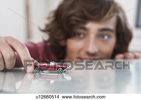 Teenage boy playing with toy car View Large Photo Image Picture - Teenage boy playing with toy car. Fotosearch