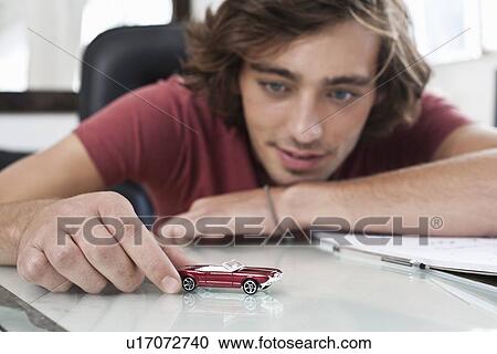 Stock Image - Teenage boy playing with toy car. Fotosearch