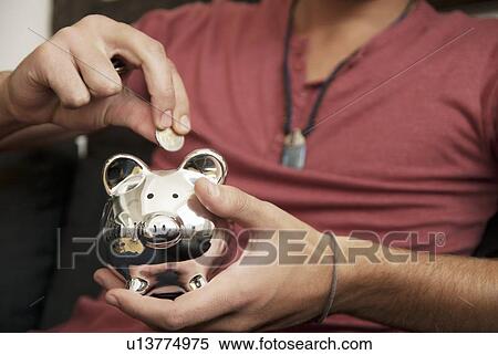 Teenage boy putting money in piggy bank View Large Photo Image Stock Photography - Teenage boy putting money in piggy bank. Fotosearch