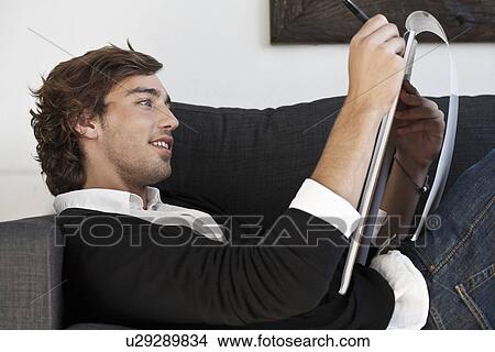 Picture - Teenage boy taking notes on sofa. Fotosearch