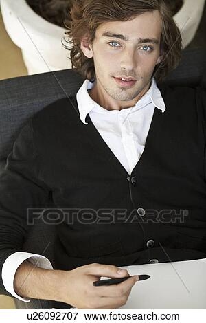 Stock Photo - Teenage boy taking notes on sofa. Fotosearch