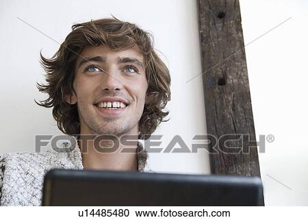 Stock Image - Teenage boy using laptop indoors. Fotosearch