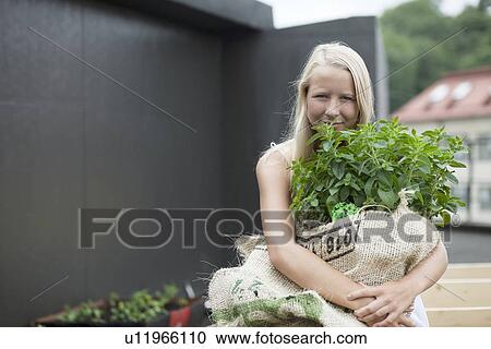 Stock Image - Teenage girl holding sack of plants. Fotosearch