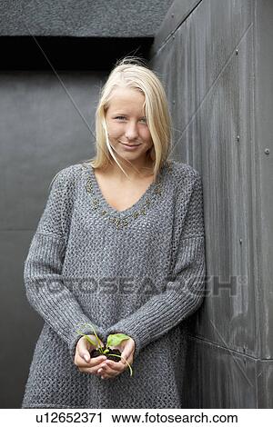 Stock Image - Teenage girl holding seedling. Fotosearch